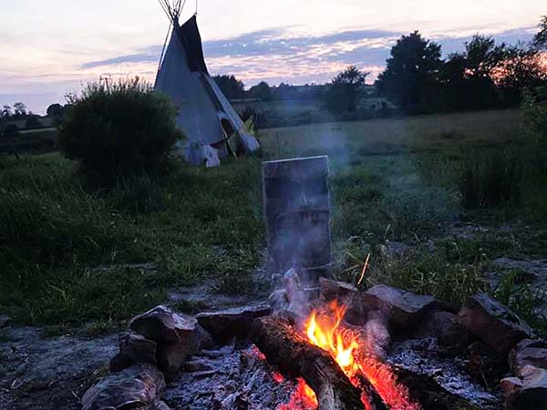 Self Healing Outdoor Fire with sunset and tipi in the background are representative of Shon's Self Healing in Wales