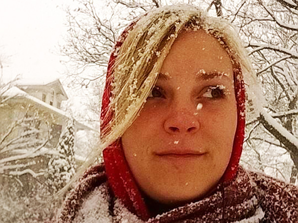Brianna Sefcak, new ND student from warm Columbia enjoys winter snow in the USA wearing a red scarf with snow-dusted blonde hair.