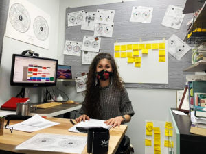 Dani Espinosa's well organized Eye on The Team Iridology office with Dani shown wearing a lockdown mask.